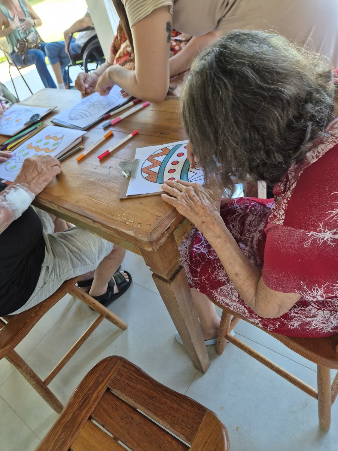 Residentes pintando desenhos em uma mesa na varanda