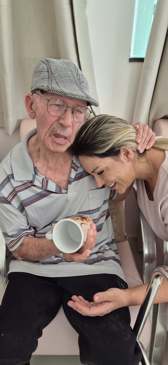 Residente segurando uma xícara enquanto recebe um abraço carinhoso