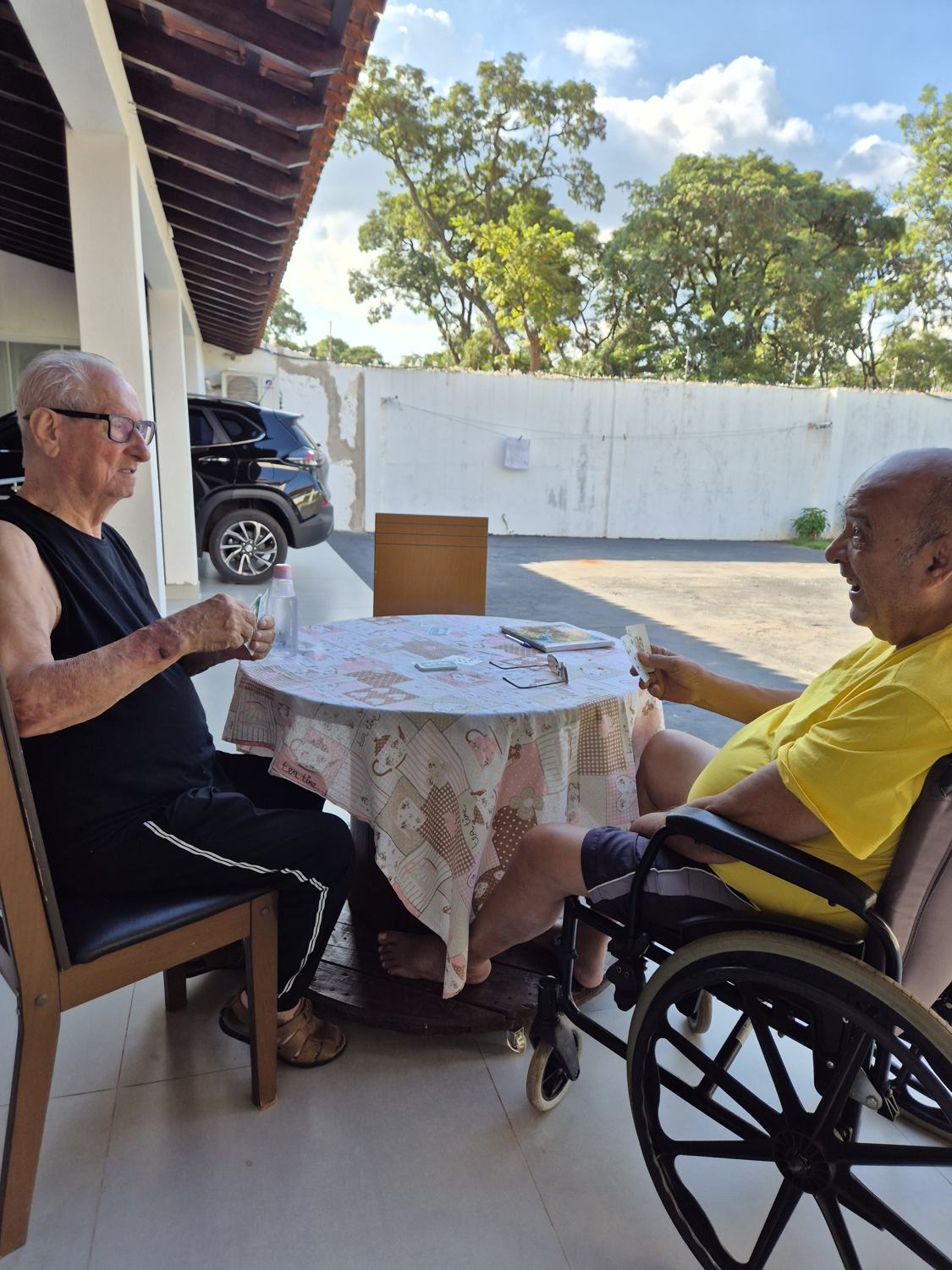 Residentes jogando cartas em uma mesa na área externa